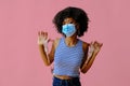 young female student with backpack wearing protective mask and posing on pink background, back to school concept Royalty Free Stock Photo