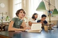 Young female student with book thoughtfully working on study project in library of university Royalty Free Stock Photo