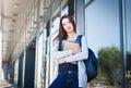 Young female IT student, with books and backpack. Staying outside before lesson and smiling Royalty Free Stock Photo
