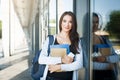 Young female IT student, with books, smartphone and backpack. Staying outside before lesson and smiling Royalty Free Stock Photo