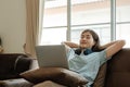 Young female student is bored and tired, wearing headphones, studying online at home.