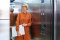 A young female student, intern, assistant holds a folder in her hands and stands, enters the elevator of the office Royalty Free Stock Photo