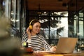 Young female student with laptop and headphones studying at table in cafe Royalty Free Stock Photo