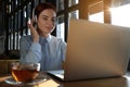 Young female student with laptop and headphones studying at table in cafe Royalty Free Stock Photo
