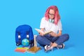 Young female student reading books while sitting on floor with backpack Royalty Free Stock Photo