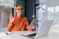 A young female student sitting in an office, co-working space, library at a table with a laptop and using a tablet to Royalty Free Stock Photo