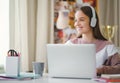 Young female student sitting at the table, using laptop when studying.