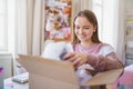 Young female student at the table, opening parcel box.