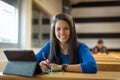 Young female student at university classroom. She`s using tablet and headphones for taking notes. Royalty Free Stock Photo