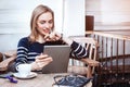 Young female student is watching movie on digital tablet while sitting in cafe, beautiful woman using laptop com Royalty Free Stock Photo