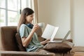 Young female student wearing headphones sits intently and happily studying online on her laptop on the sofa in the Royalty Free Stock Photo