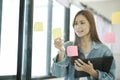 Young female student writing study plans on post-its on glass wall. Royalty Free Stock Photo