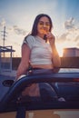 Young female in sunglasses and white t-shirt is eating pizza while posing standing in yellow car cabriolet. Fast food Royalty Free Stock Photo