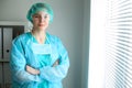 Young female surgeon doctor standing with arms crossed and smiling at hospital. Royalty Free Stock Photo