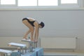 Young female swimmer in low position on starting block in a swimming pool. Royalty Free Stock Photo