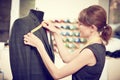 Female tailor works with male suit