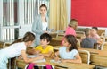 Female teacher controlling group work of interested tweens at lesson Royalty Free Stock Photo