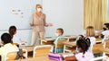 Female teacher in protective mask giving lesson to children Royalty Free Stock Photo