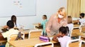 Female teacher in protective mask giving lesson to children Royalty Free Stock Photo