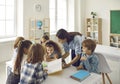 Young female teacher reading with group of elementary school pupils in classroom Royalty Free Stock Photo