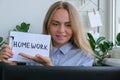 Young female teacher sitting at desk and using laptop showing HOMEWORK text at home. e Education Back to school. Student Royalty Free Stock Photo