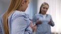 Young female touching chest in front of mirror, unsatisfied with her breast size Royalty Free Stock Photo