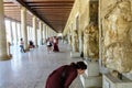 A young female tourist admiring an artifact at The Stoa of Attalos as other tourists walk by exploring the site, in the Agora