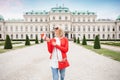 A young female tourist with the Austrian flag enjoys a tour of Vienna in the garden of the Belvedere Palace Complex