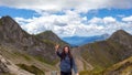Young female tourist on the background of a mountain panorama. Victory sign, two fingers.
