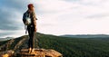 A young female tourist with a backpack admires the sunset from the top of the mountain, panorama. Royalty Free Stock Photo