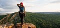 A young female tourist with a backpack admires the sunset from the top of the mountain. A traveler on the background of mountains Royalty Free Stock Photo