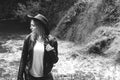 Young female tourist with backpack and cowboy hat looking at the river washed away the bridge, the crossing was impossible. Deep