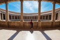 Young female tourist with backpack enjoying wide galleries with columns in the inner circular patio in Palace of Charles V in Royalty Free Stock Photo