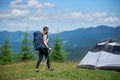 Woman tourist near camping in the mountains with backpack and trekking sticks in the morning Royalty Free Stock Photo