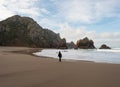 Young female tourist with camera walking along Praia da Ursa atlantic coast rock cliff sand beach Sintra Lisbon Portugal