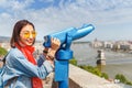 Female tourist looking through city telescope on the old town of Budapest. Travel and view point concept