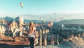 Young female tourist with colorful hot air balloon flying over Cappadocia landscape Royalty Free Stock Photo