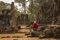 Young female tourist in red dress taking a picture of the historic Bayon Temple, Angkor Wat, Cambodia