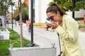 Young female tourist refreshes herself and drinks water from the city fountain tap on the street. Girl got sunstroke sick from the Royalty Free Stock Photo