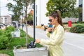 Young female tourist refreshes herself and drinks water from the city fountain tap on the street. Girl got sunstroke sick from the Royalty Free Stock Photo