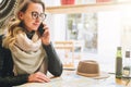 Young female tourist is sitting in cafe at table and talking on cell phone. Girl is calling her friend. Tourism, travel. Royalty Free Stock Photo