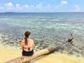 A young female tourist sitting on a log on the secluded remote tropical island of Laughing bird caye Royalty Free Stock Photo