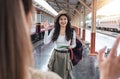 young female tourist smiles and greets a fellow passenger she just met while waiting for a train at the train station.