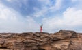 Young female tourist stands on a rock in the middle of the Mekong River in the dry season at Sam Phan Bok