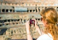 Young female tourist takes a picture inside the Coliseum in Rome Royalty Free Stock Photo