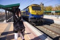 Young female tourist talking on the phone while a freight train with unknown destination. Royalty Free Stock Photo