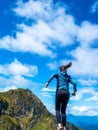 A young female tourist on top of a mountain jumps into the sky. Happiness and a sense of freedom,