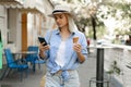 Young female tourist walking through the old town eating ice cream and using a smartphone to search for a map online Royalty Free Stock Photo