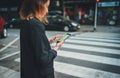 Young female tourist walking In street crosswalk enjoying big city and using app with city touristic map on mobile phone online Royalty Free Stock Photo