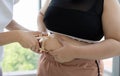 Young female trainer measuring fat layer of overweight woman with caliper at fitness Royalty Free Stock Photo